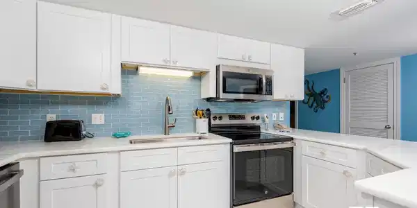 Image 3: Kitchen featuring appliances with stainless steel finishes, white cabinets, light tile patterned floors, light stone counters, and tasteful backsplash