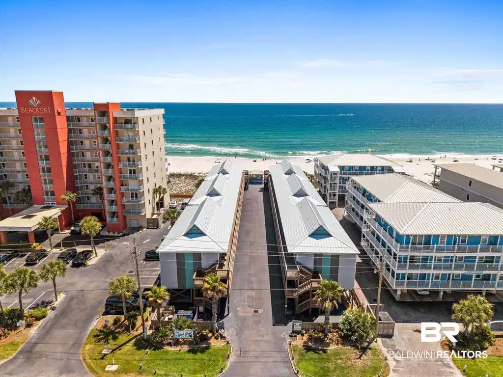 Image 1: Aerial view of waterfront with a beach and apartment complex