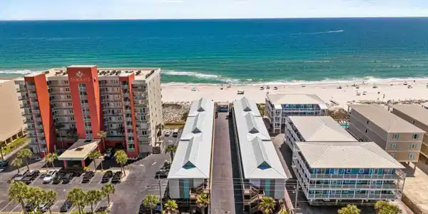 Image 3: Aerial view of waterfront with a beach and apartment complex / building