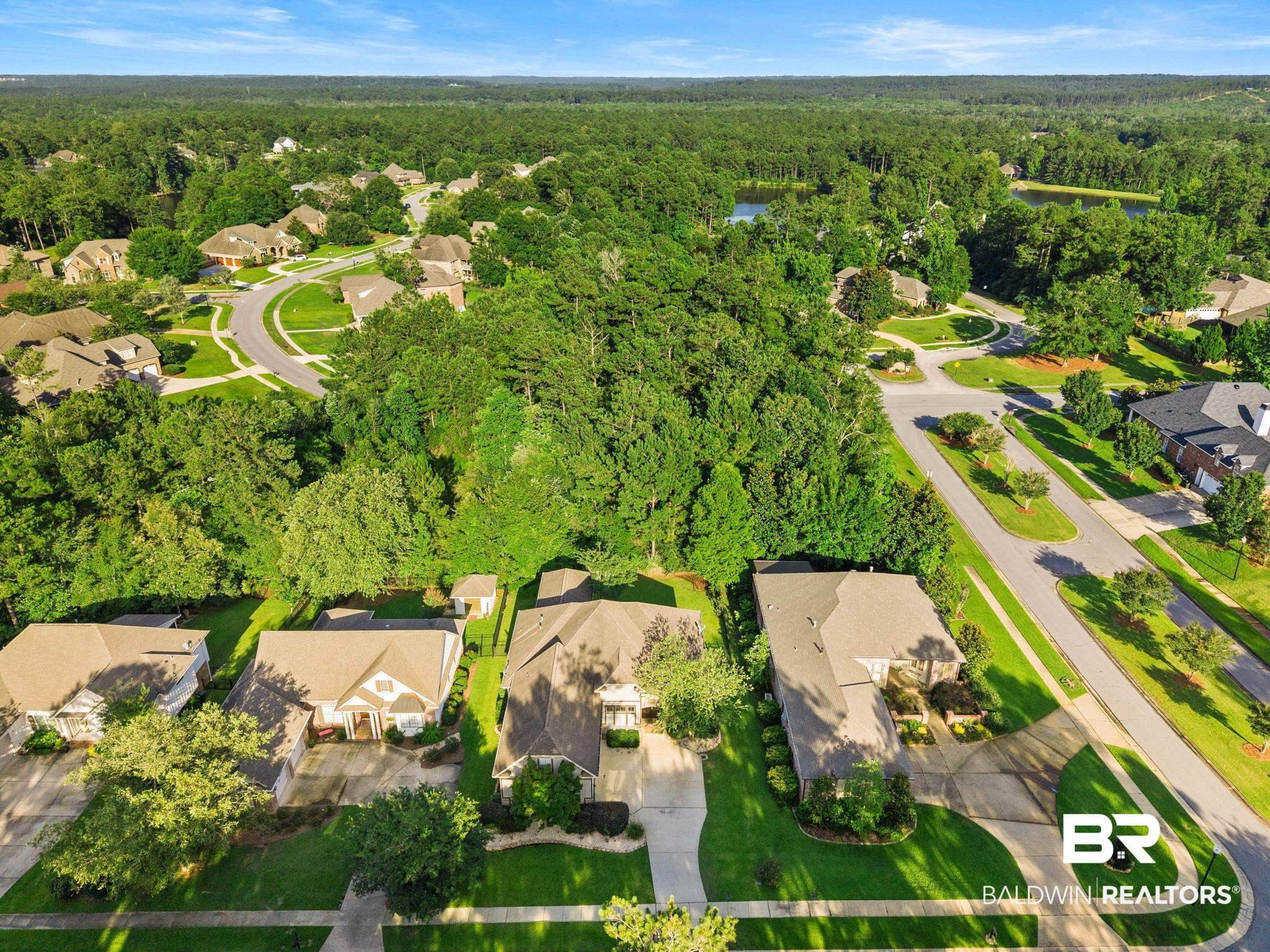 Image 4: Aerial perspective highlighting the property with a light-colored roof, surrounded by mature trees and manicured lawns