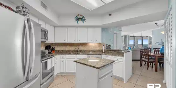 Image 2: Kitchen with backsplash, appliances with stainless steel finishes, light tile patterned flooring, a peninsula, and a center island