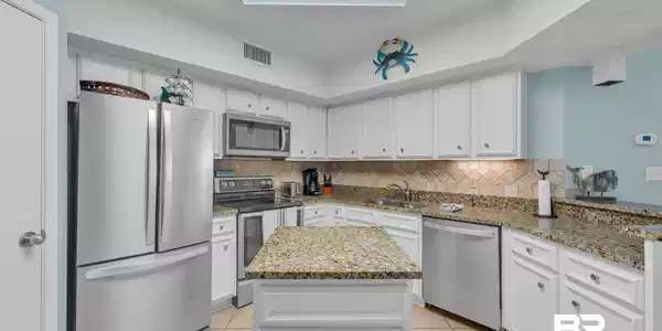 Image 3: Kitchen with appliances with stainless steel finishes, light tile patterned floors, tasteful backsplash, and white cabinetry