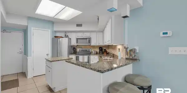 Image 4: Kitchen with backsplash, a peninsula, stainless steel appliances, dark stone countertops, and white cabinets