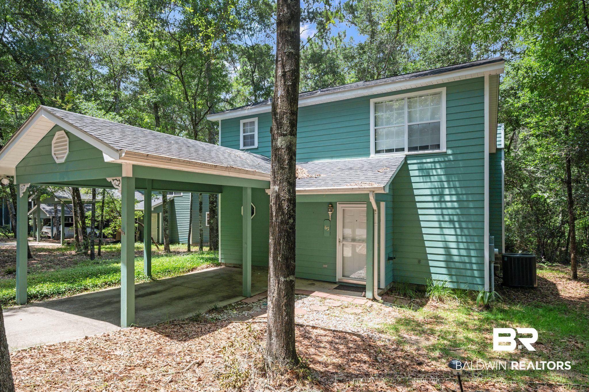 Image 3: Exterior featuring green horizontal siding, a carport with a gable roof, and a white entry door