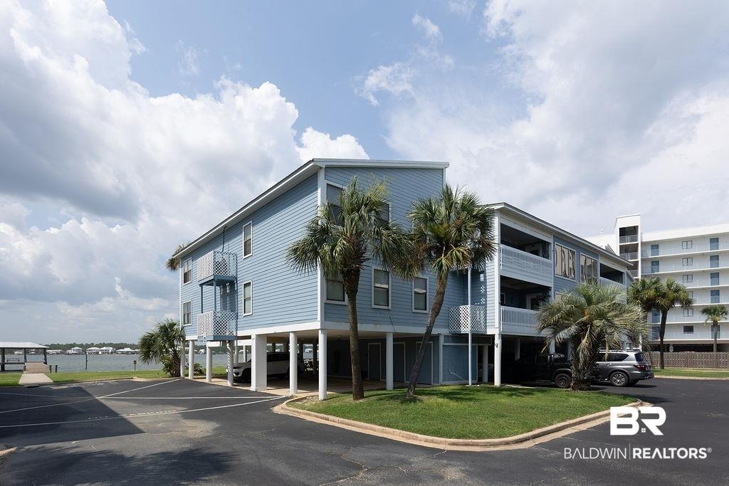 Image 2: Multi-story coastal building with light blue siding, multiple balconies, and a ground-level parking area
