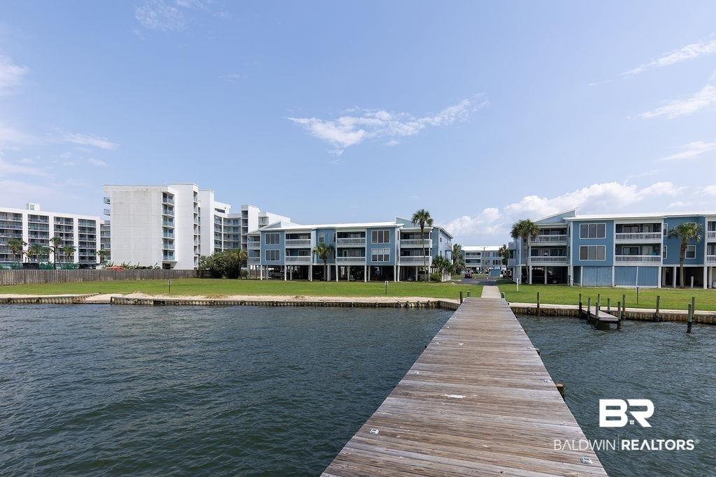 Image 3: Wooden pier extending into a body of water, bordered by a grassy shoreline and coastal buildings