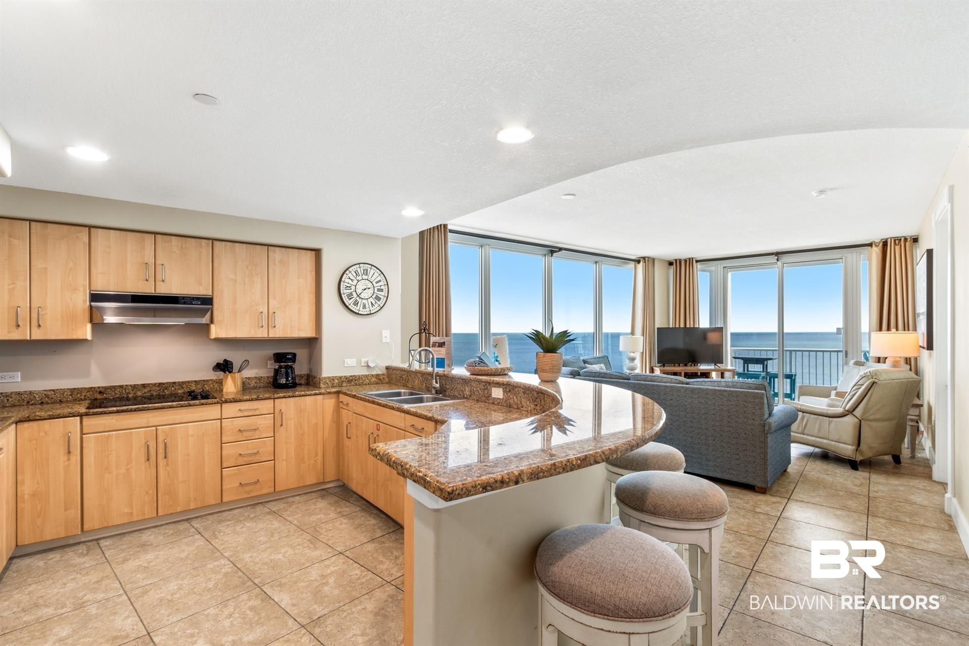 Image 3: Kitchen featuring a peninsula, open floor plan, dark stone countertops, a kitchen breakfast bar, and expansive windows