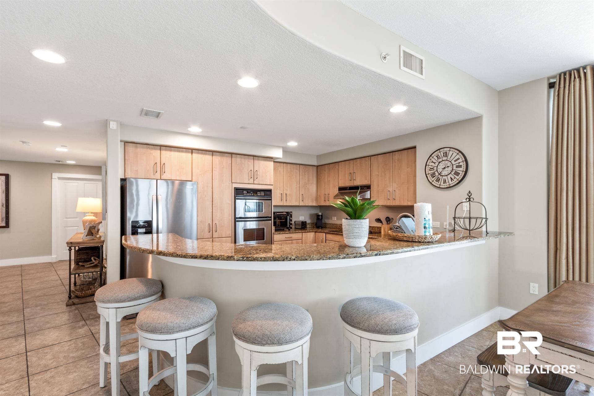 Image 4: Kitchen featuring dark stone countertops, recessed lighting, light tile patterned floors, stainless steel appliances, and a peninsula