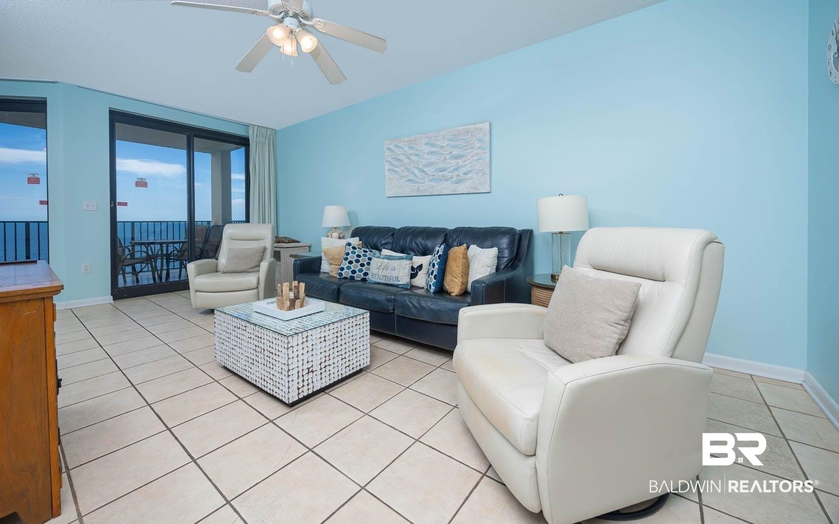 Image 2: Living area with light tile patterned floors and ceiling fan