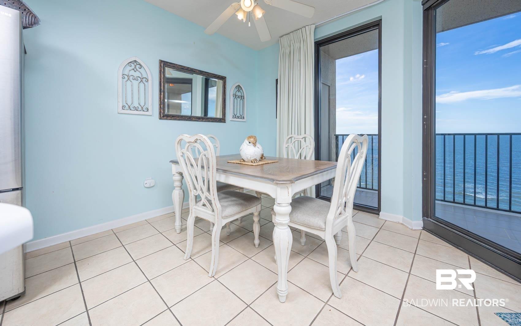 Image 3: Dining space with light tile patterned floors, a water view, and a ceiling fan