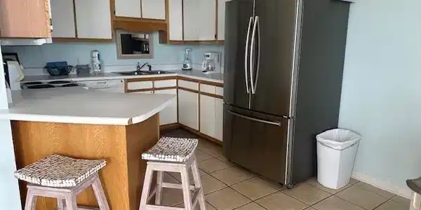 Image 4: Kitchen featuring light countertops, white cabinets, a kitchen bar, freestanding refrigerator, and a peninsula