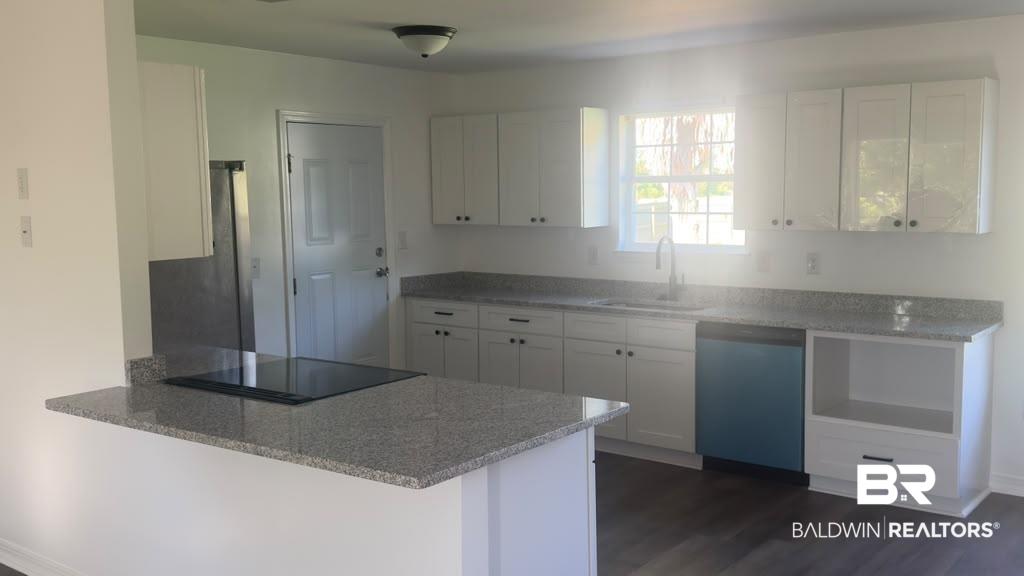 Image 3: Modern kitchen featuring white shaker cabinetry, stainless steel appliances, speckled stone countertops, and wood-finish flooring