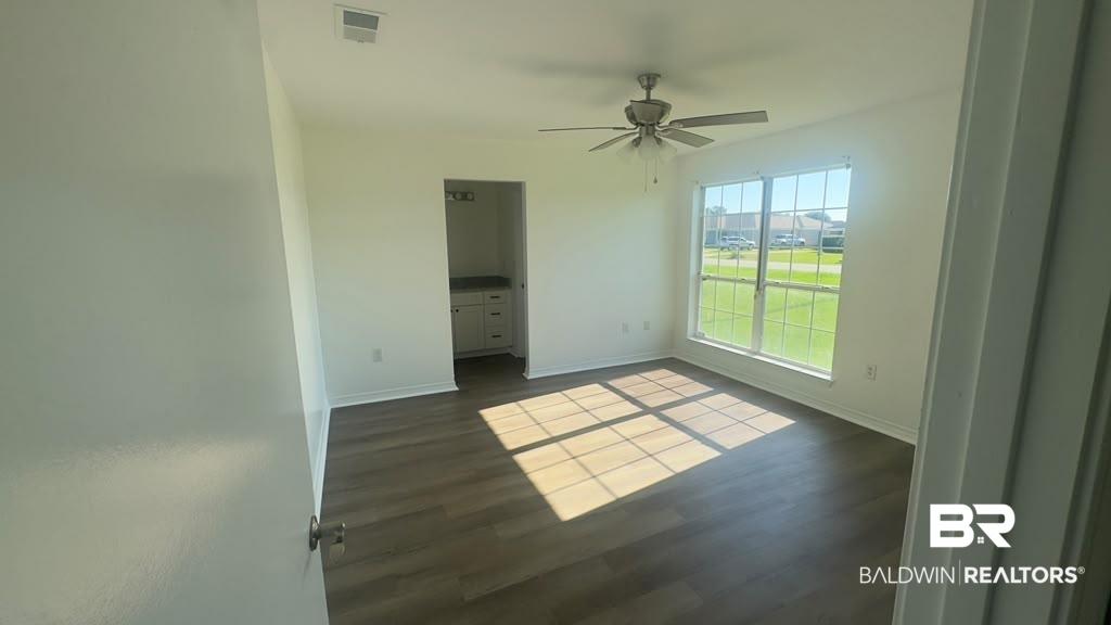 Image 4: Spacious room featuring wood-finish flooring, a ceiling fan with integrated lighting, and a large multi-pane window
