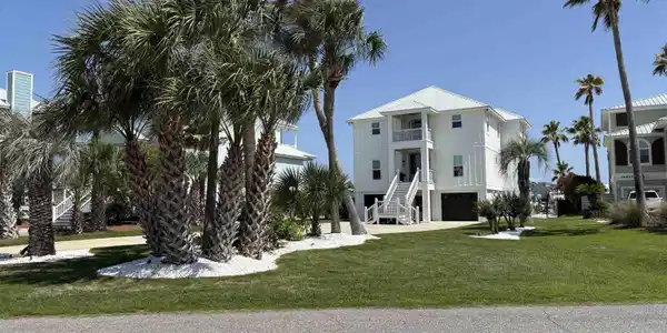 Image 3: Stilted white residence featuring a metal roof, multiple balconies, a ground-level garage, and an elevated entrance staircase