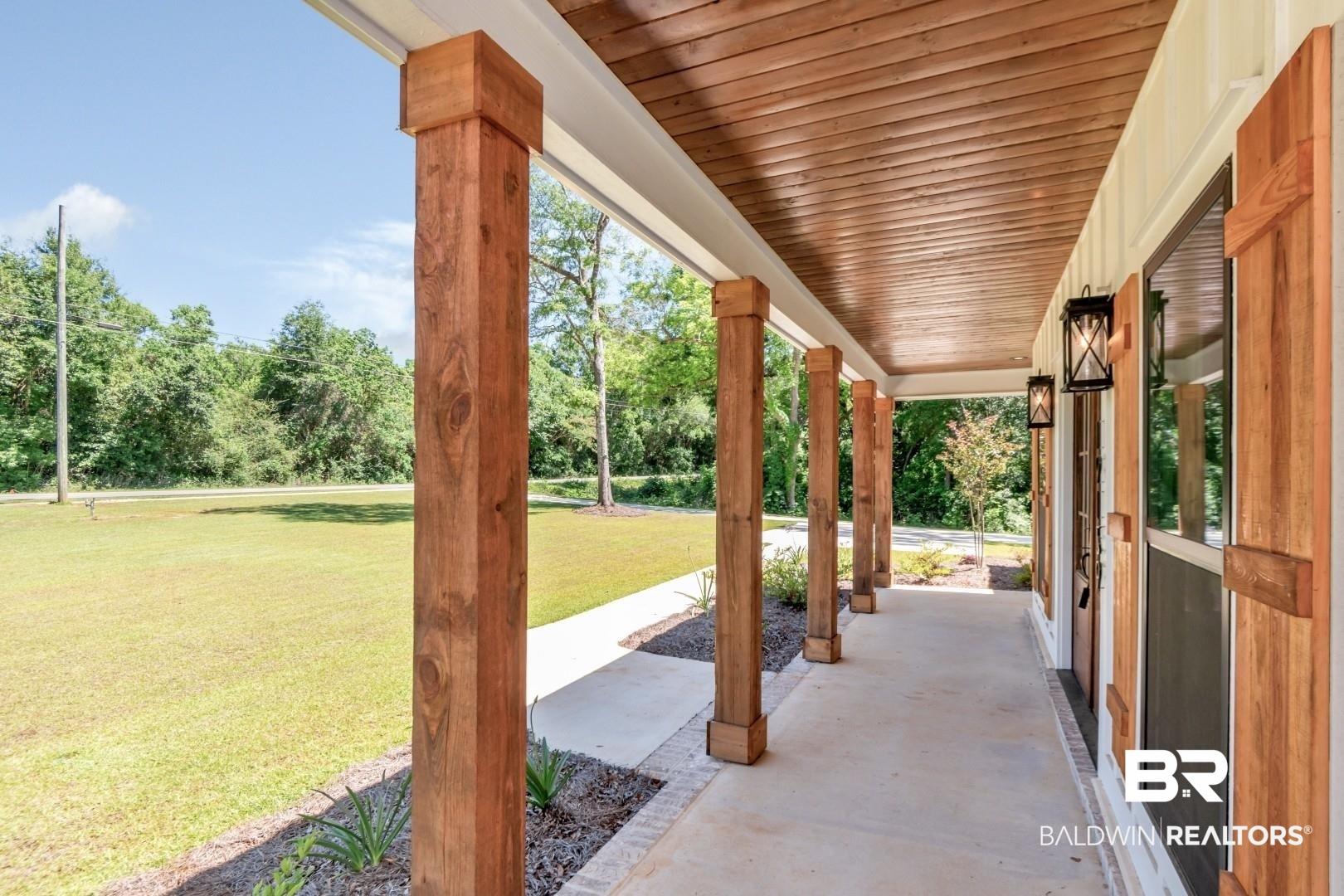 Image 3: Expansive front porch featuring multiple wood posts, a wood-paneled ceiling, and concrete flooring