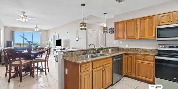 Image 4: Kitchen featuring wood cabinetry, appliances with stainless steel finishes, a peninsula with eat-up breakfast bar