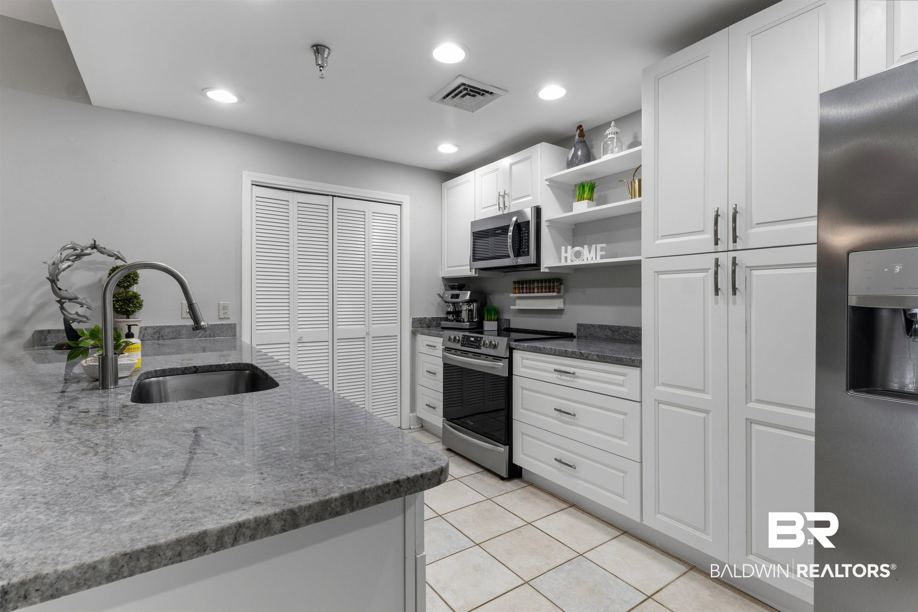 Image 2: Kitchen featuring white cabinetry, granite countertops, stainless steel appliances, and recessed lighting