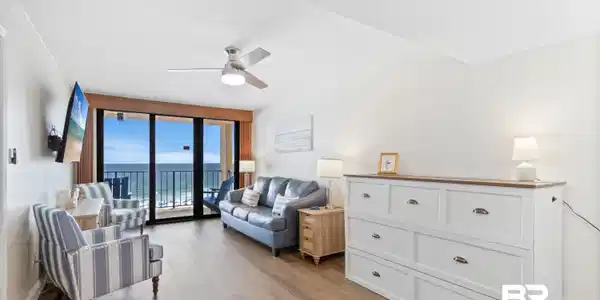 Image 4: Living area featuring wood-finish flooring, a ceiling fan with integrated lighting, and direct balcony access through sliding glass doors