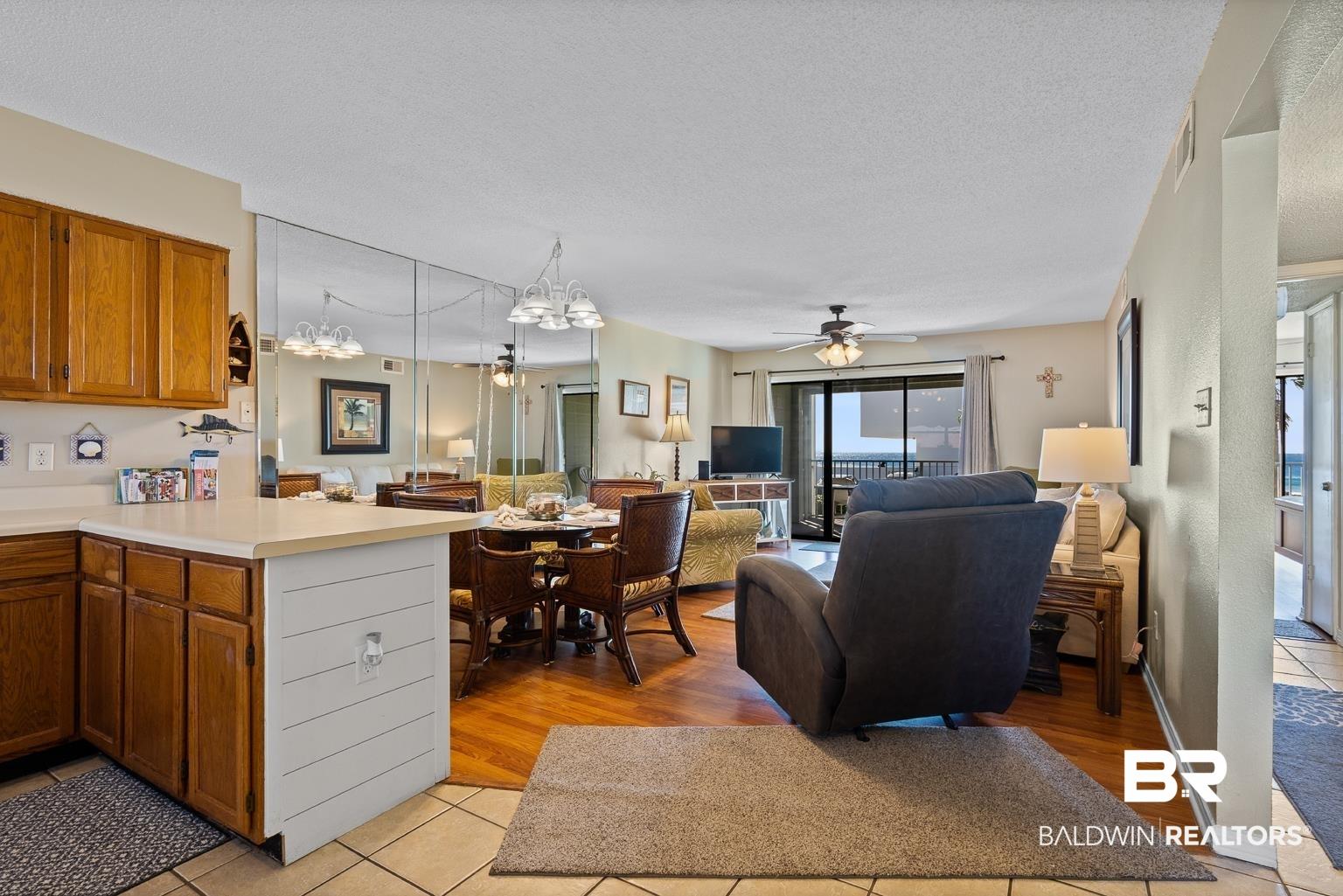 Image 4: Kitchen with light hardwood / wood-style floors, hanging light fixtures, kitchen peninsula, a textured ceiling, and ceiling fan with notable chandelier