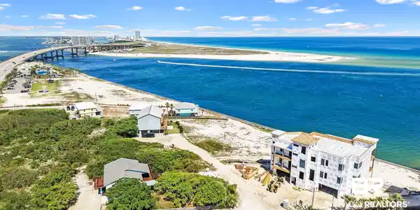 Image 3: Coastal property featuring a multi-story structure under construction, surrounded by natural vegetation