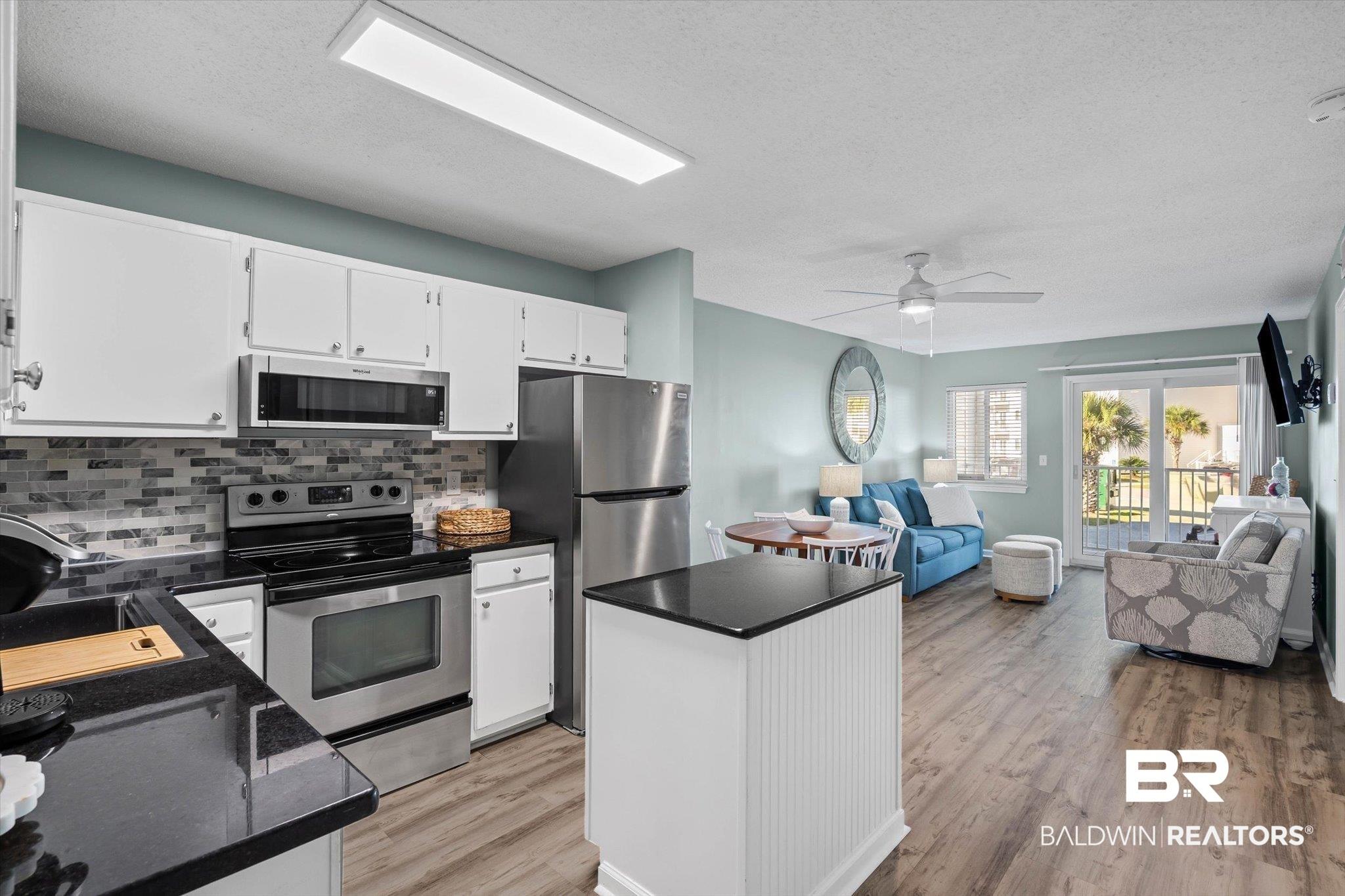 Image 2: Kitchen featuring stainless steel appliances, open floor plan, backsplash, white cabinets, and a kitchen island