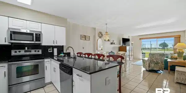 Image 4: Kitchen with a breakfast bar, appliances with stainless steel finishes, dark stone counters, open floor plan, and a peninsula