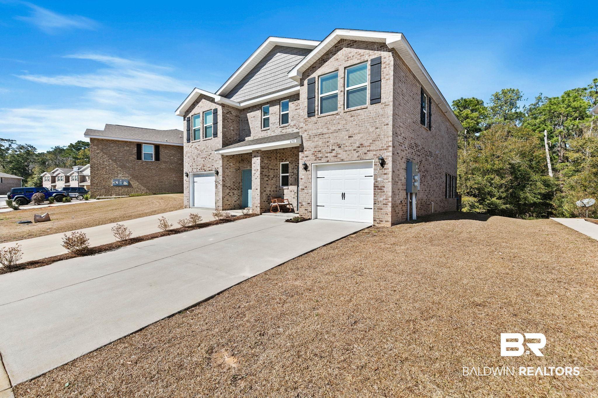 Image 3: View of front facade with an attached garage, brick siding, and concrete driveway