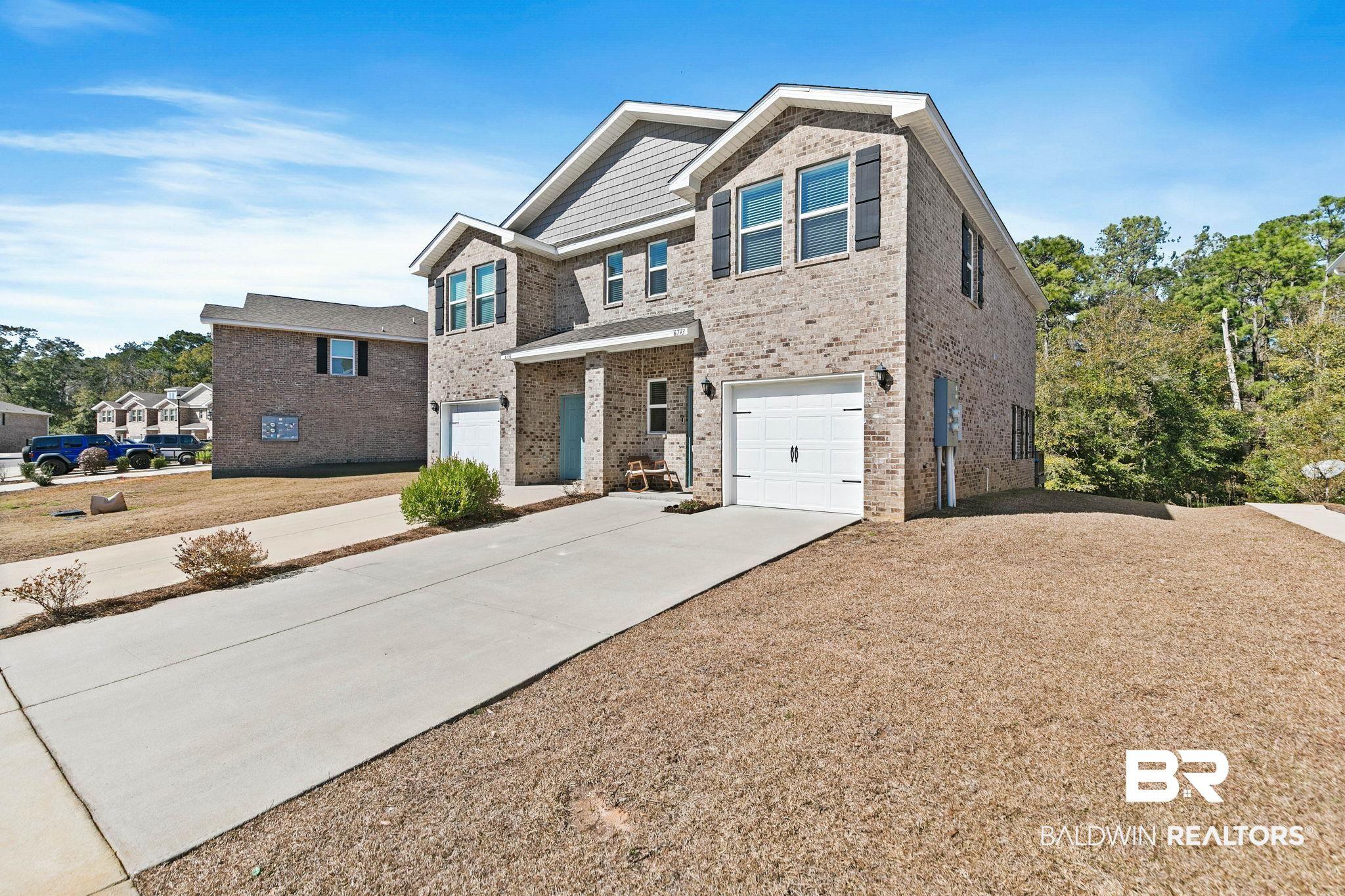 Image 4: Craftsman-style home featuring brick siding, a garage, driveway, and covered porch