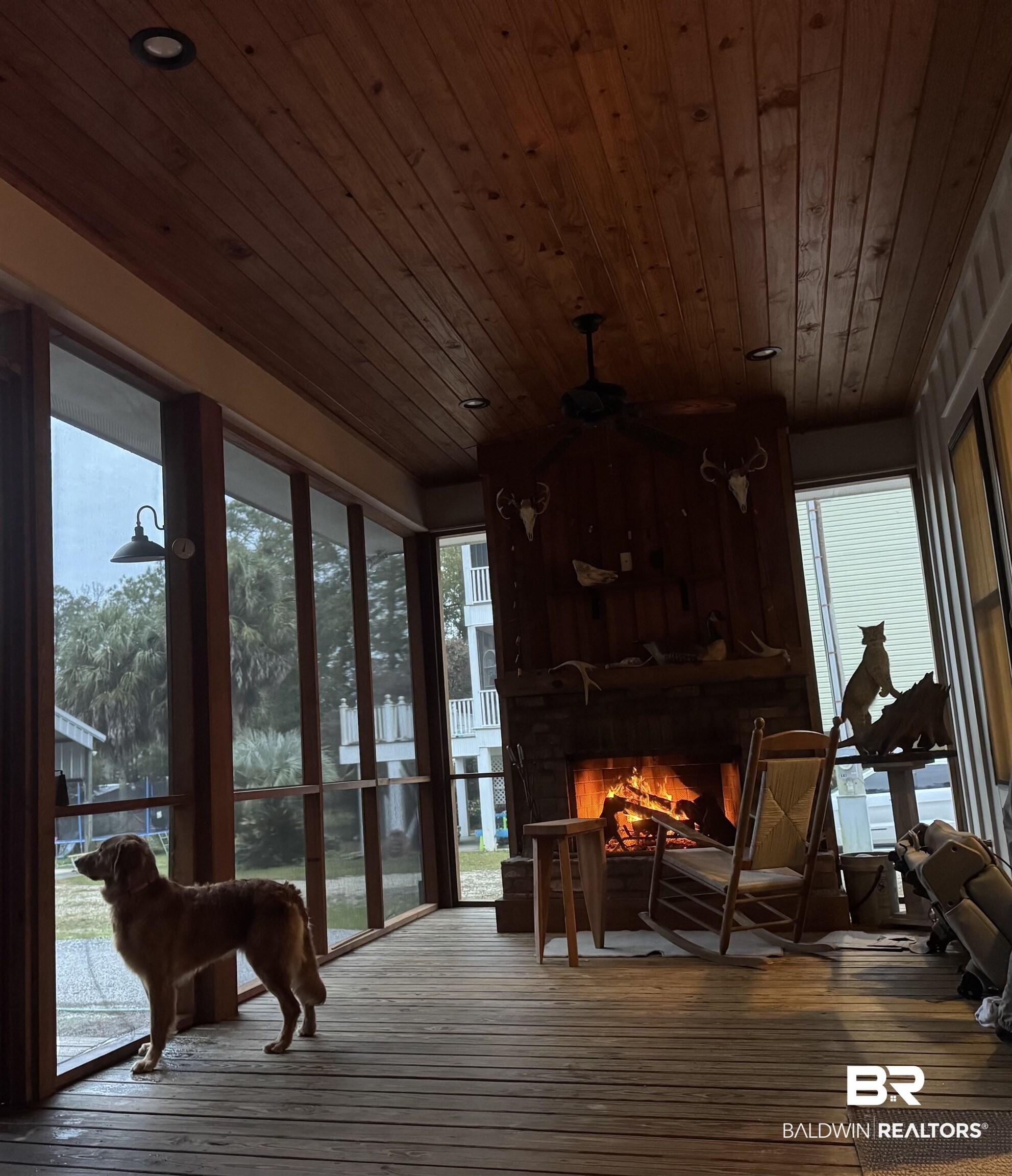 Image 4: Spacious screened porch featuring a stone fireplace, wood-finish flooring, plank wood ceiling, recessed lighting, and a ceiling fan