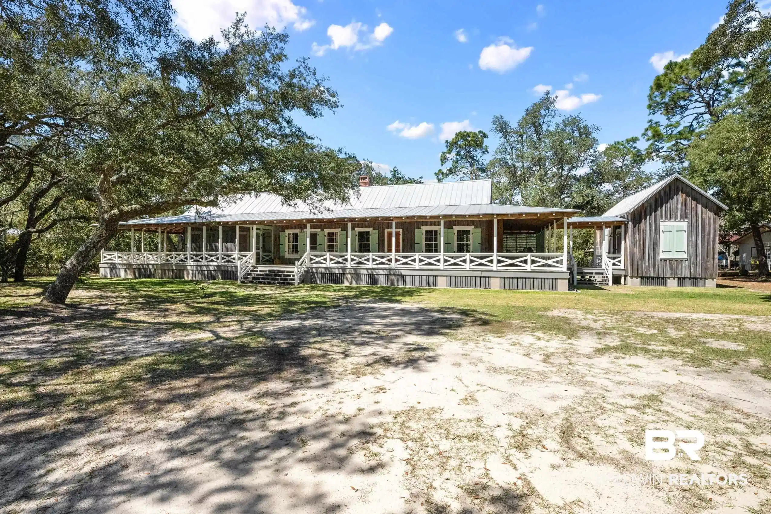 Image 1: View of front of house with metal roof, covered porch, a chimney, and board and batten siding
