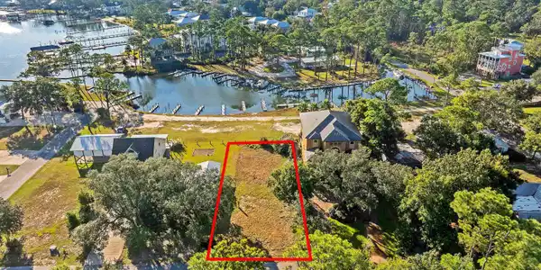 Image 3: Aerial view of property and surrounding area with property boundaries highlighted and a large body of water