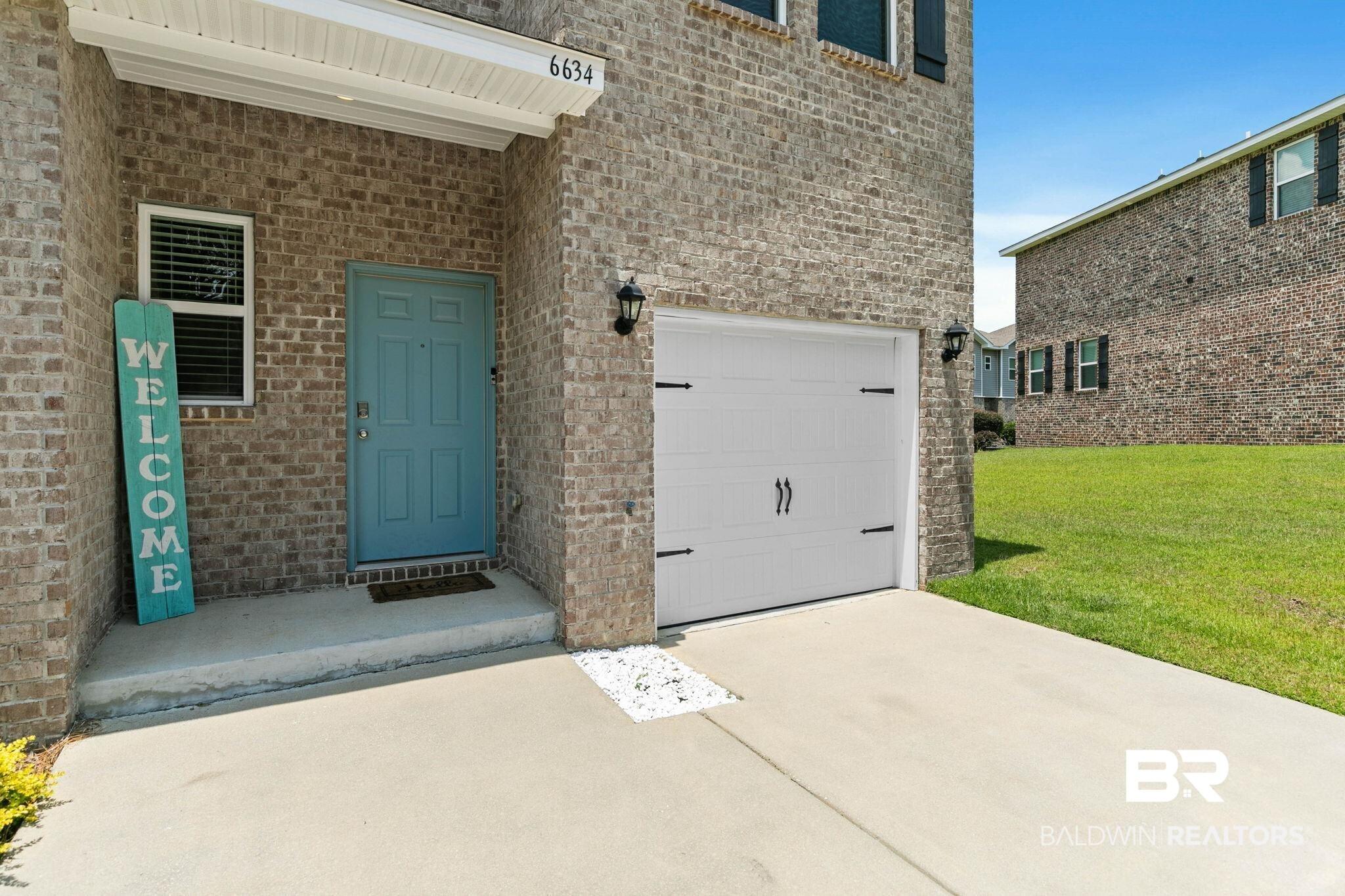 Image 4: Brick exterior featuring a light blue entry door and an attached single-car garage