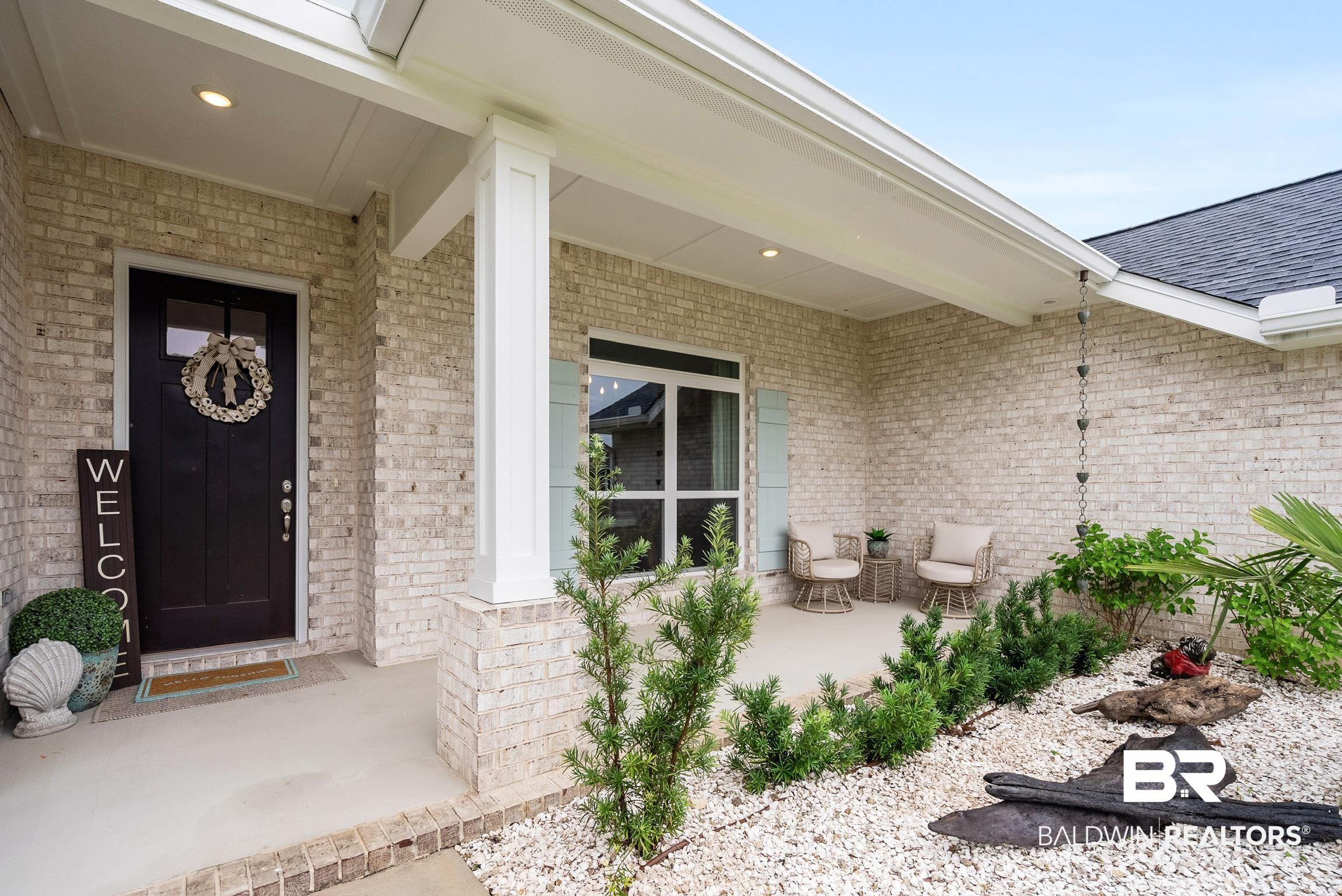 Image 3: Covered front entry featuring brick construction and a dark paneled door with glass insert