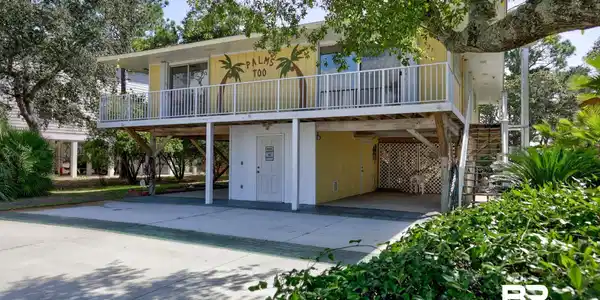 Image 2: View of front facade with stairs, a carport, and driveway