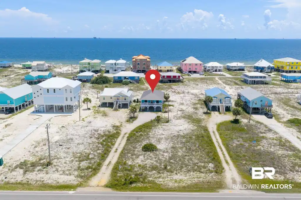 Image 1: Coastal home featuring a light blue exterior, white trim, and a covered porch