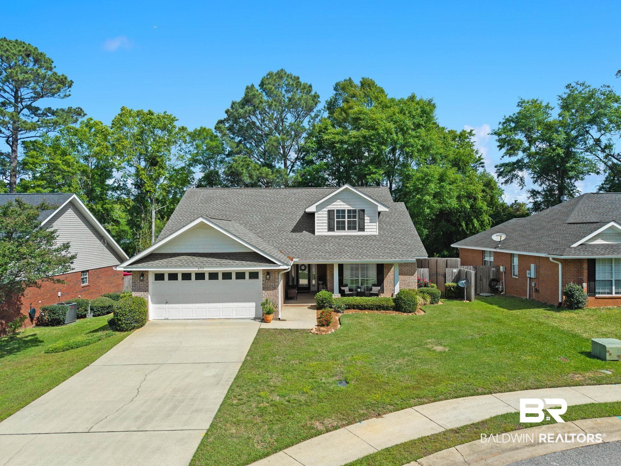 Image 2: View of front facade with a front lawn, a shingled roof, concrete driveway, an attached garage, and brick siding
