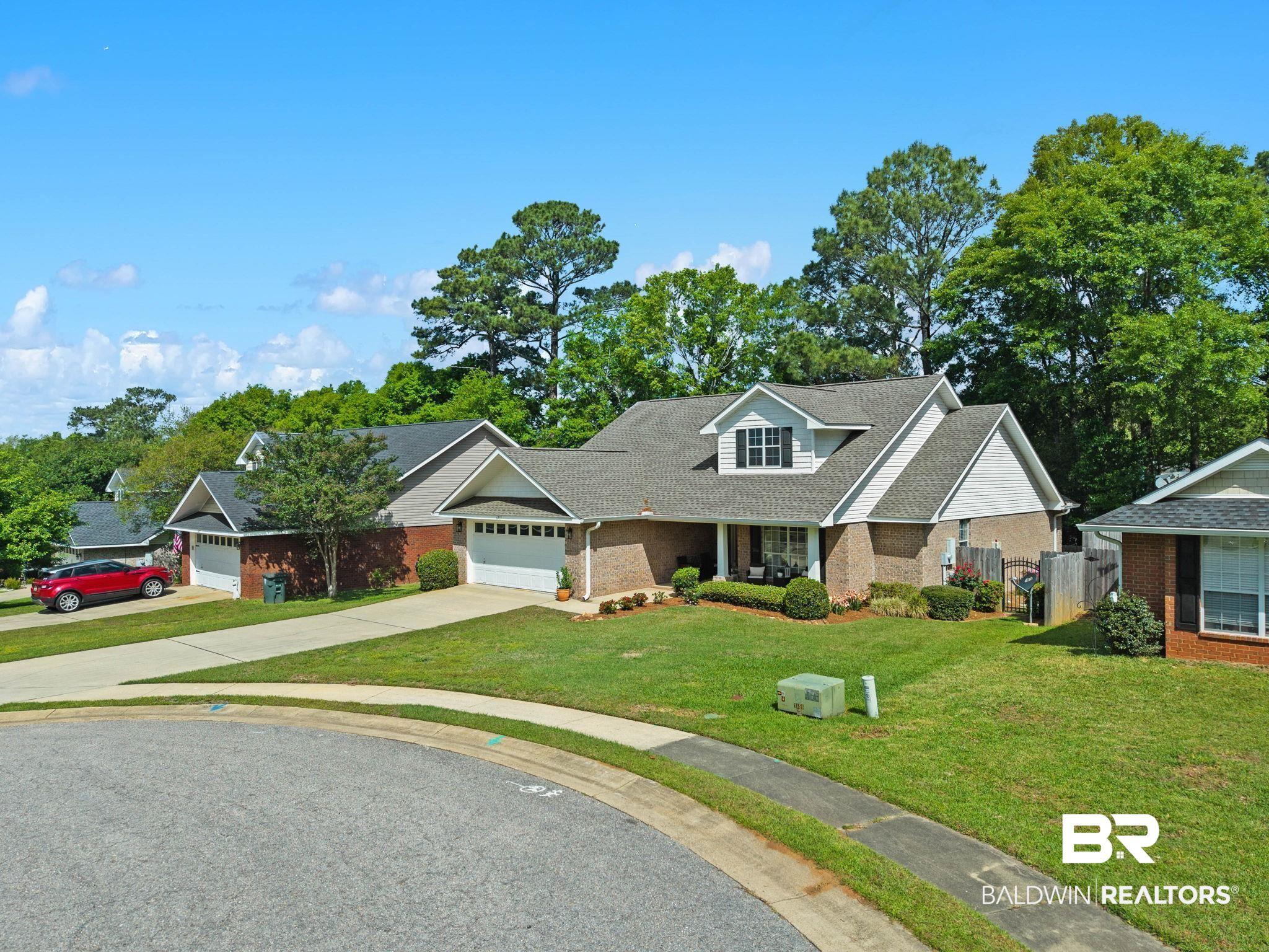 Image 3: View of front of home featuring driveway, an attached garage, brick siding, and covered porch