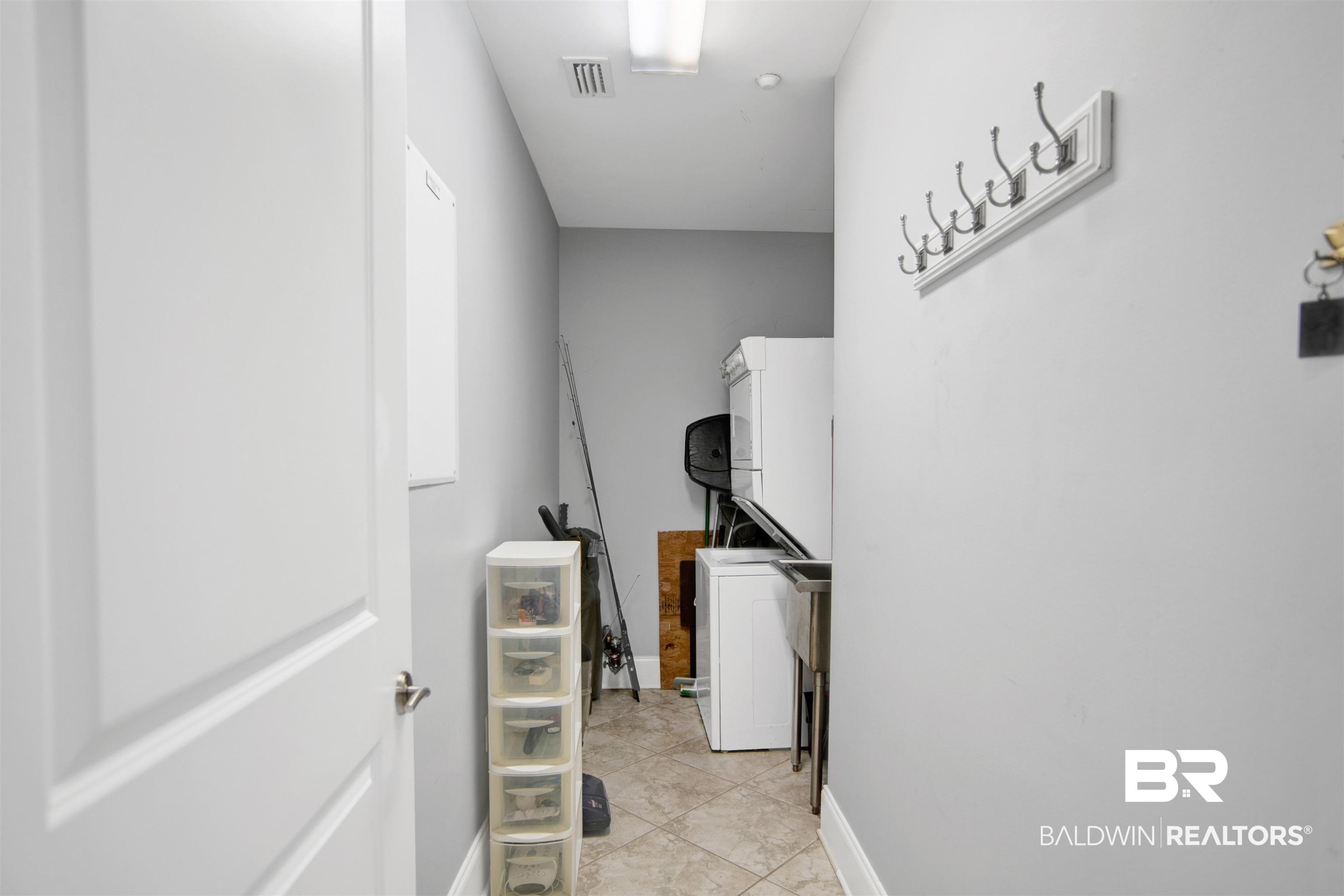 Image 3: Utility area featuring a built-in stainless steel sink, tiled flooring, and a wall-mounted coat rack