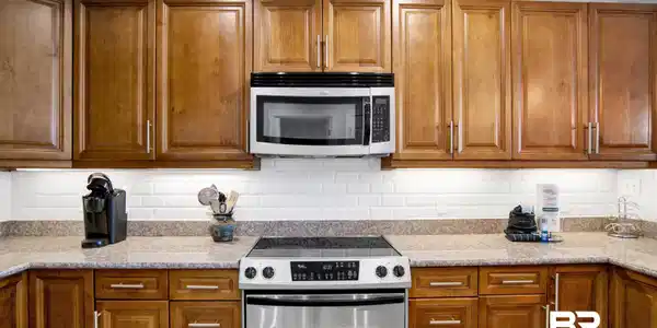 Image 4: Kitchen featuring light wood cabinetry, stone-finish countertops, stainless steel appliances, and a subway tile backsplash