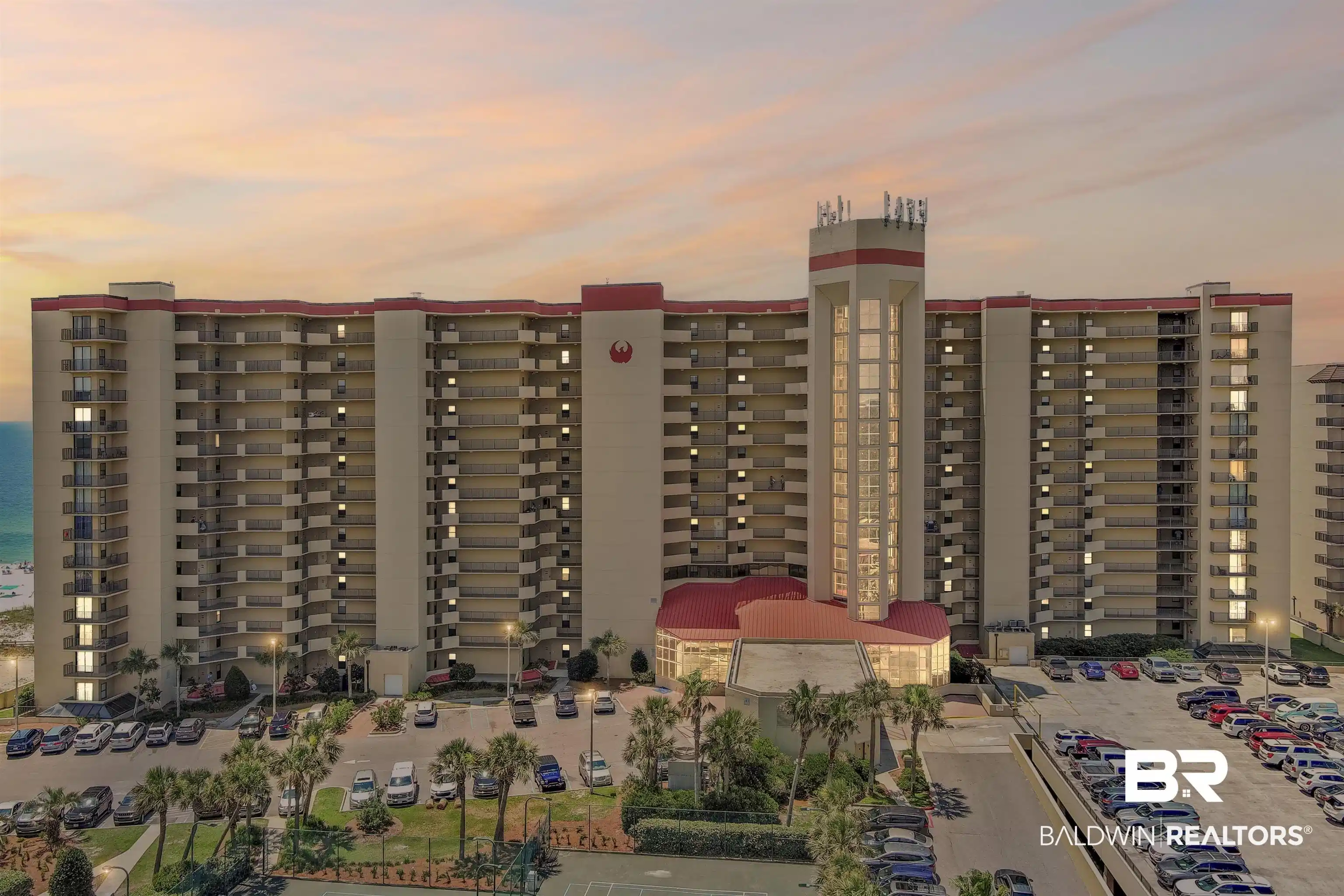 Image 1: Multi-story condominium building featuring numerous balconies, a prominent central tower element, and a beachside location