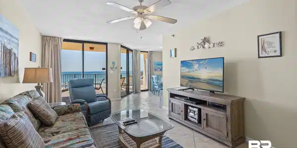 Image 2: Living area featuring tiled flooring, a ceiling fan with integrated lighting, and direct access to a balcony with ocean views through sliding glass doors