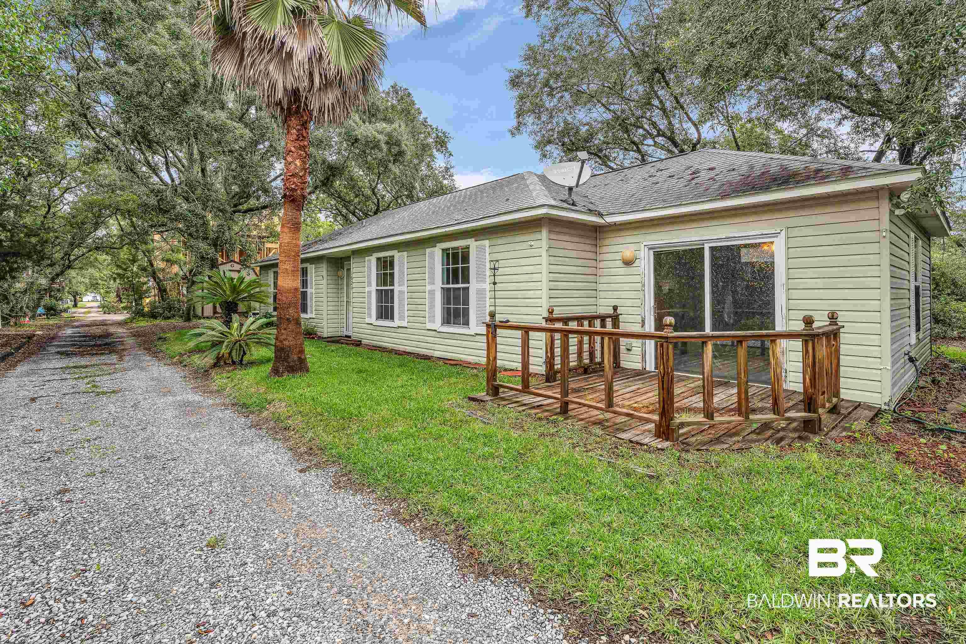 Image 1: Light green siding exterior with white window shutters and a wood deck