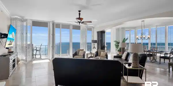 Image 2: Living room featuring crown molding, expansive windows, ceiling fan, a chandelier, and a water view