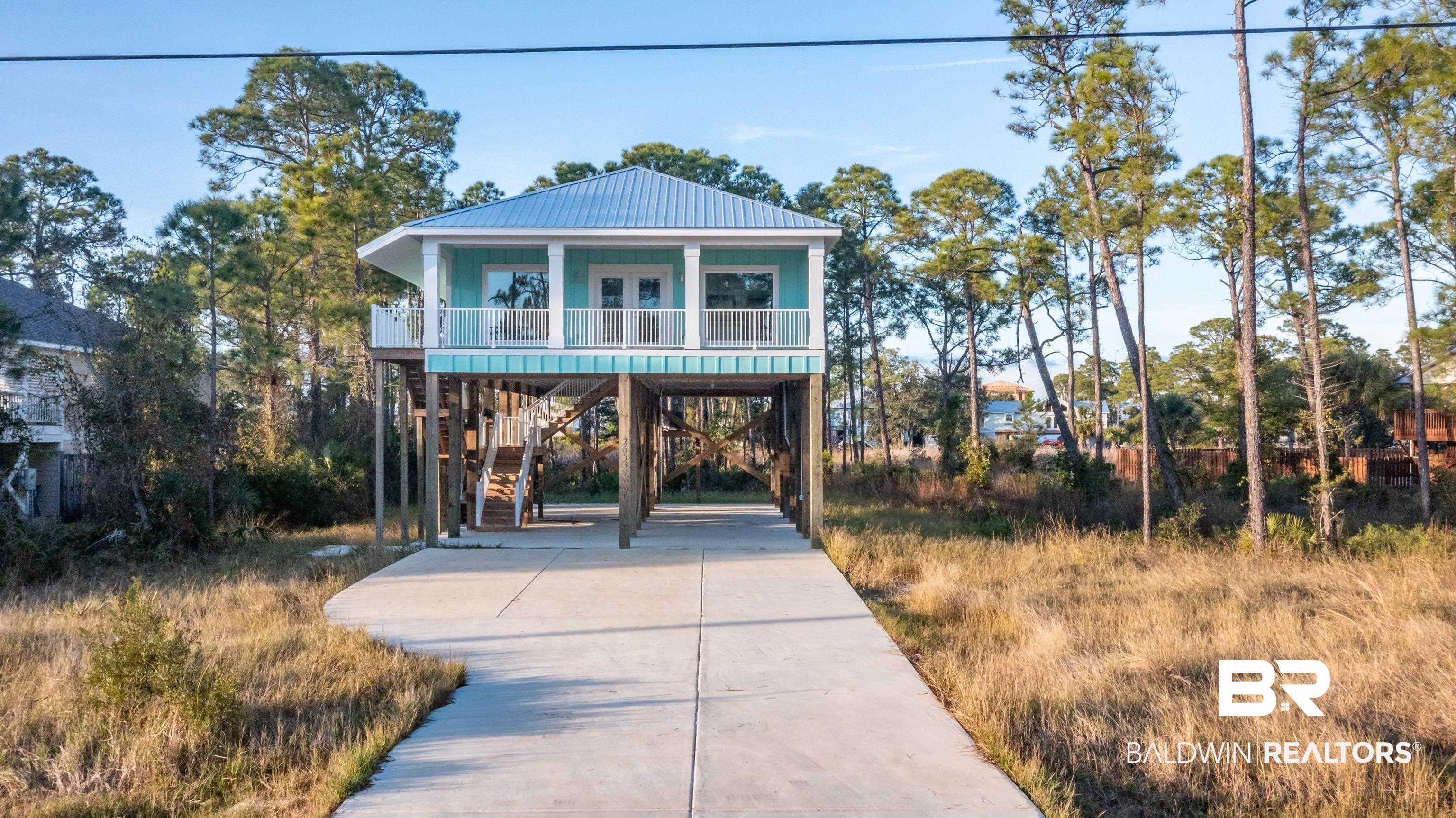 Image 2: Raised beach house featuring a carport, a metal roof, concrete driveway, and stairway