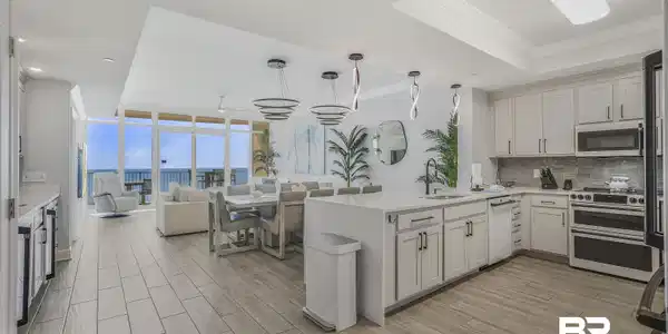 Image 3: Kitchen featuring wood tiled floors, hanging light fixtures, open floor plan, light stone countertops, and a peninsula