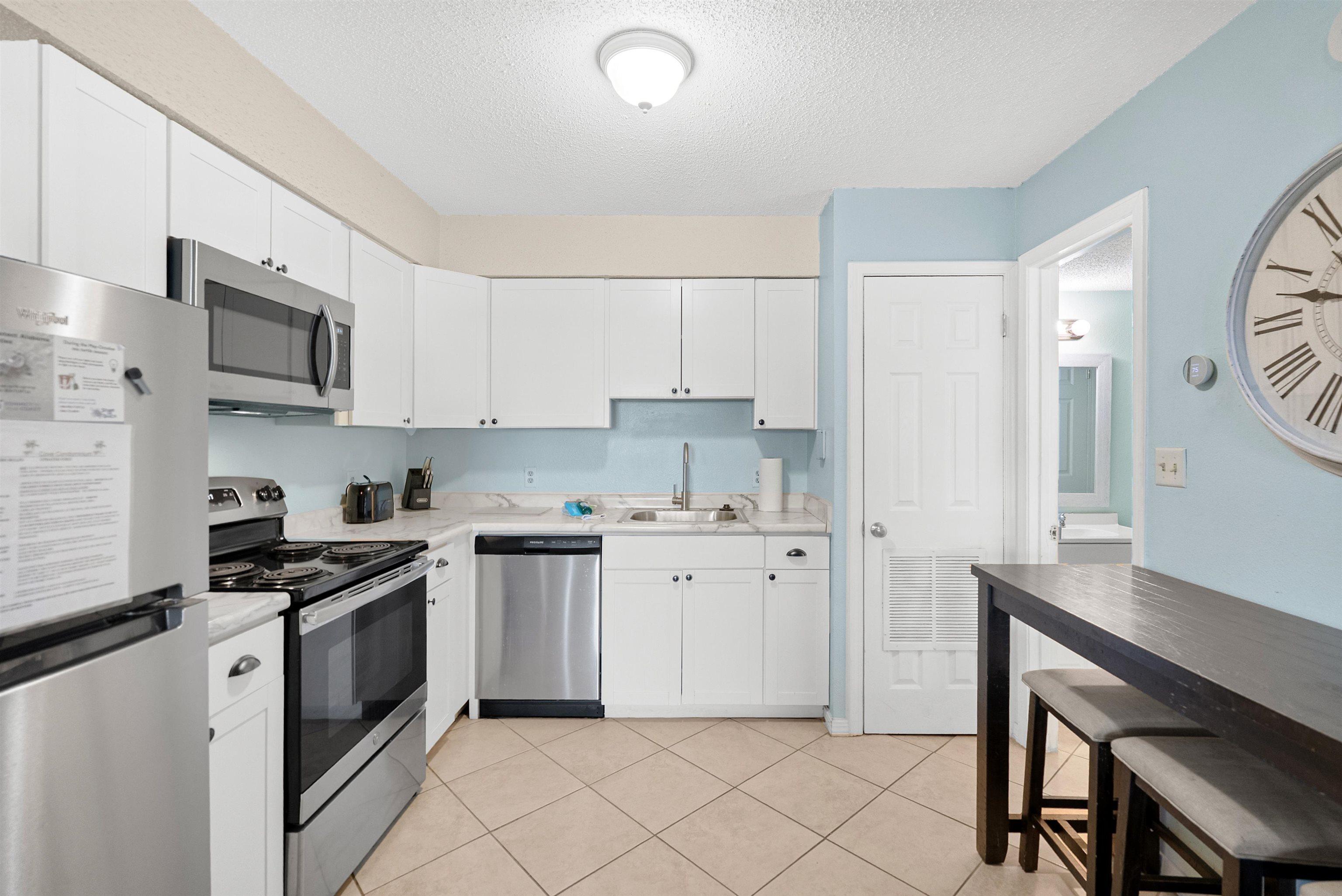 Image 3: Kitchen featuring stainless steel appliances, light countertops, white cabinets, a textured ceiling, and light tile patterned flooring