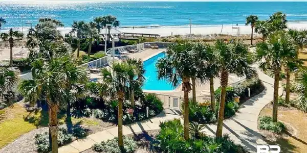 Image 3: Bird's eye view of a pool area and expansive beach