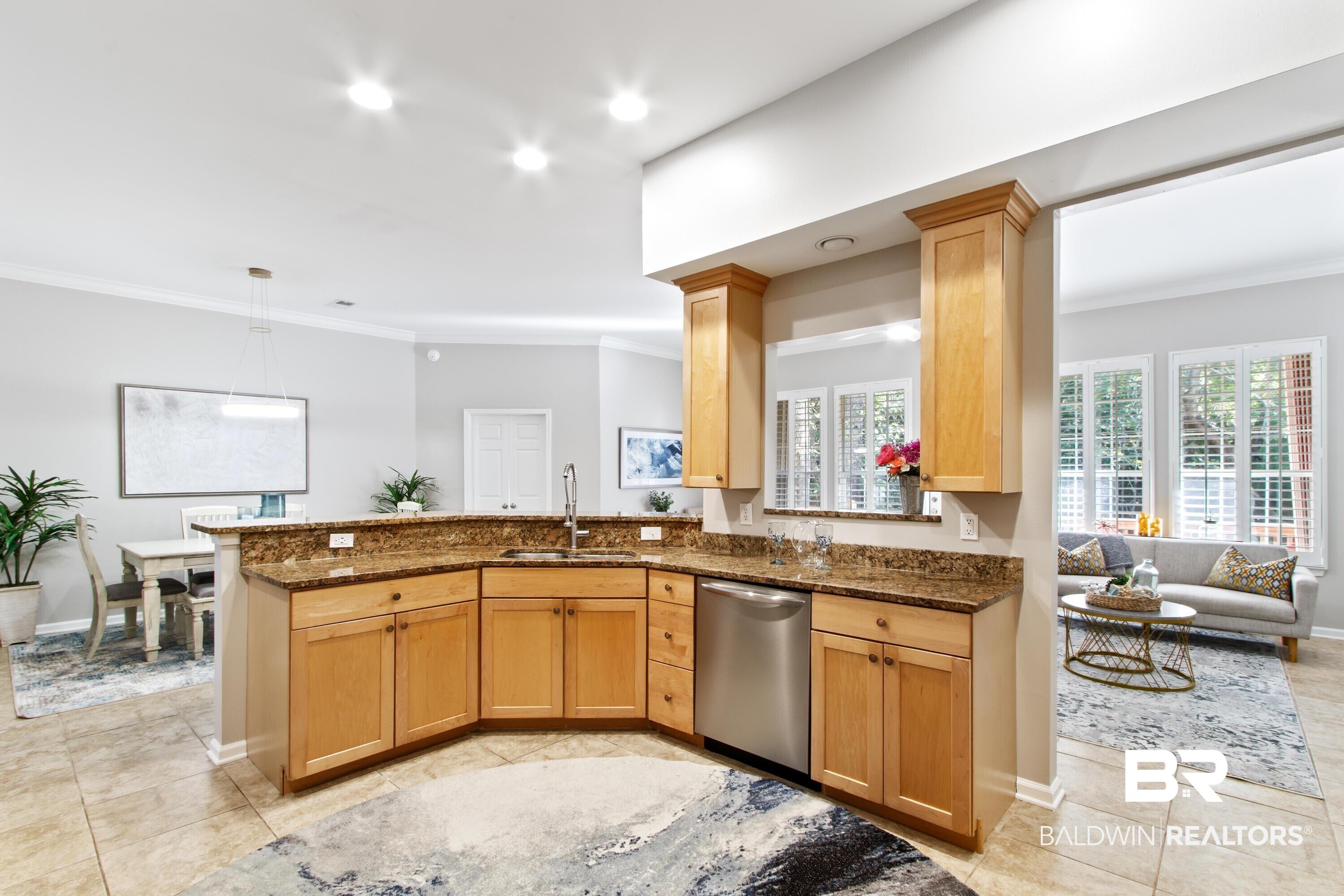 Image 4: Kitchen with crown molding, dark stone countertops, decorative light fixtures, light tile patterned flooring, and stainless steel dishwasher