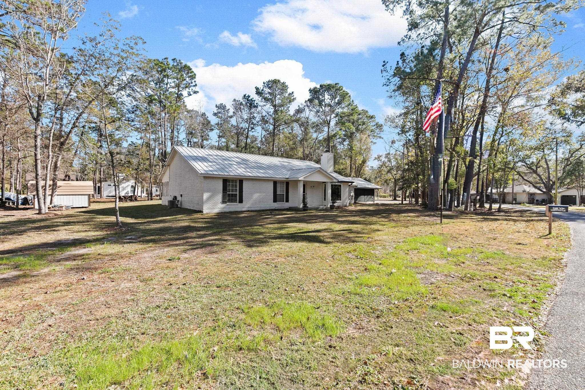 Image 3: View of front of home with a metal roof, a chimney, and a front yard