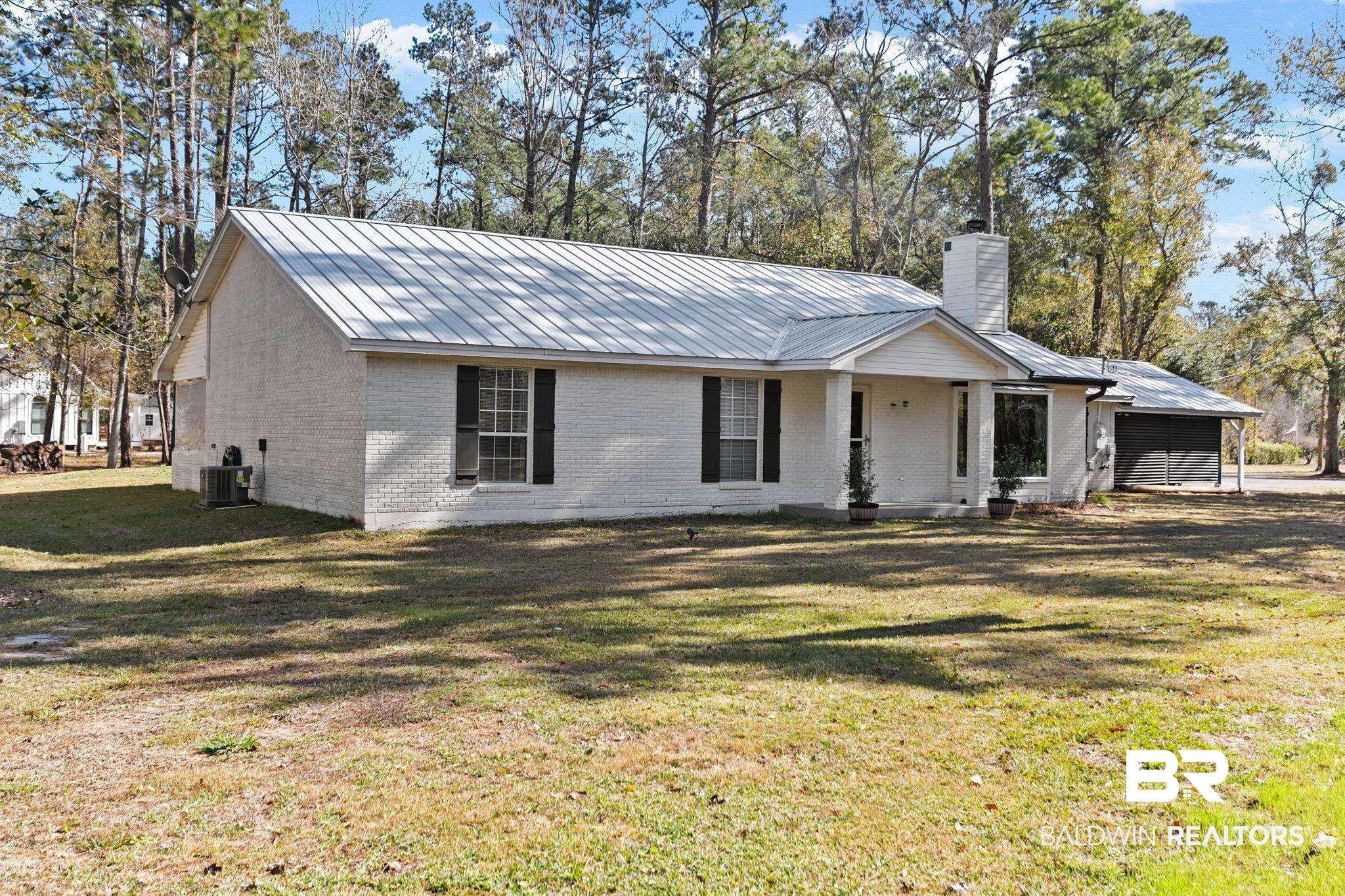 Image 4: Ranch-style house featuring a metal roof, brick siding, a front yard, a chimney, and covered porch